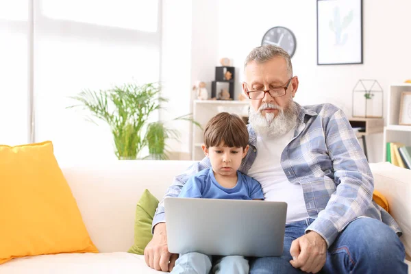 Χαριτωμένο μικρό αγόρι και ο παππούς του με μοντέρνο φορητό υπολογιστή στο σπίτι — Φωτογραφία Αρχείου