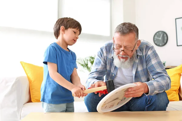 Grandfather teaching little boy to repair clock at home — Stock Photo, Image