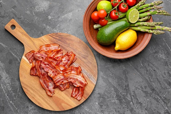 Board with fried bacon on grey background — Stock Photo, Image