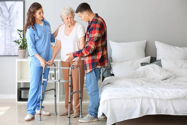 Senior woman with her grandson and caregiver in nursing home — Stock Photo, Image