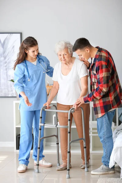 Senior woman with her grandson and caregiver in nursing home — Stock Photo, Image