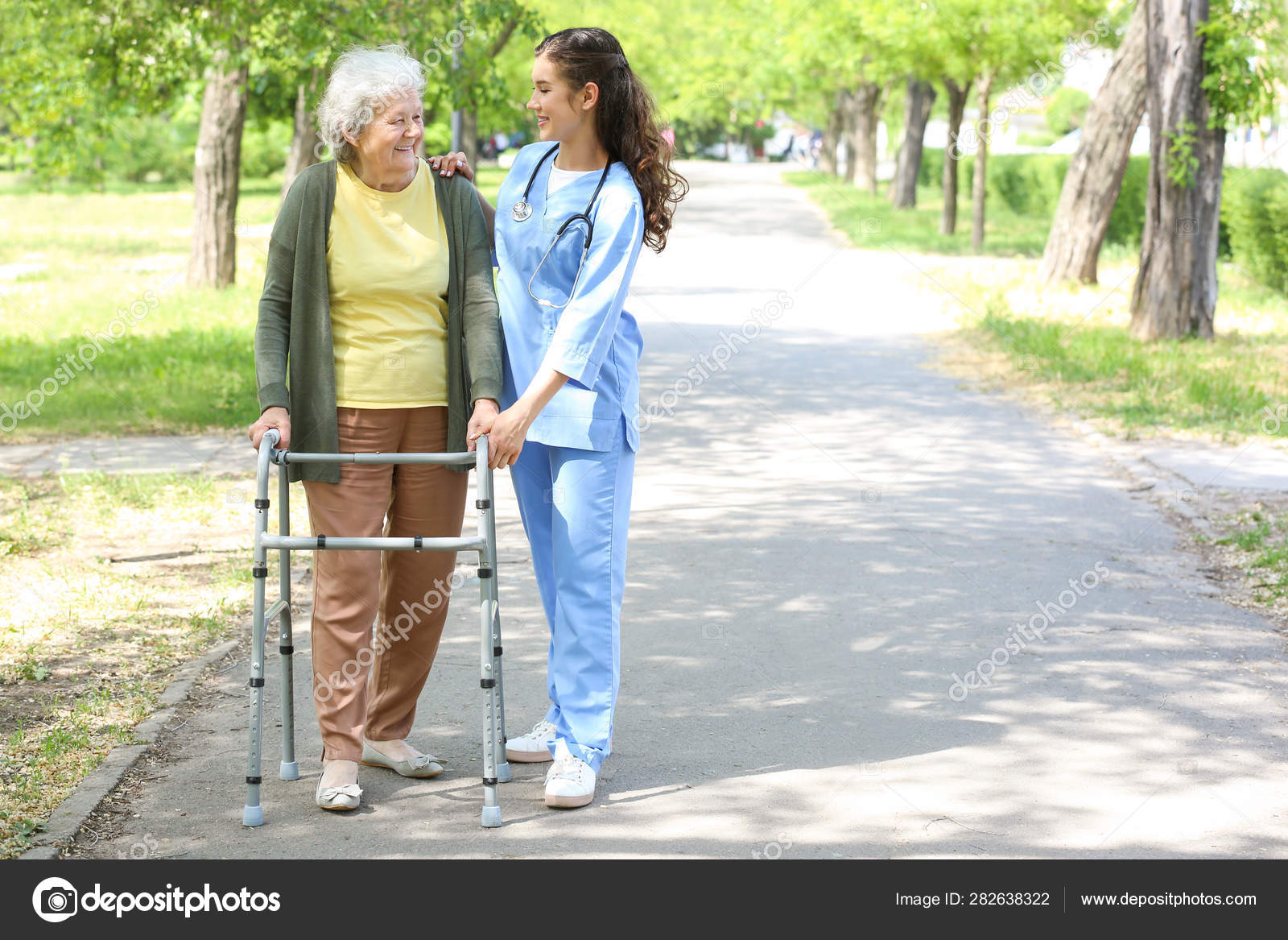 Caregiver walking with senior woman in park — Stock Photo © serezniy