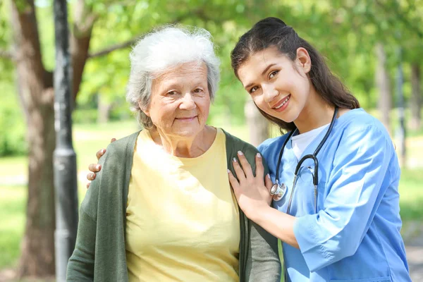 Verzorger wandelen met senior vrouw in Park — Stockfoto