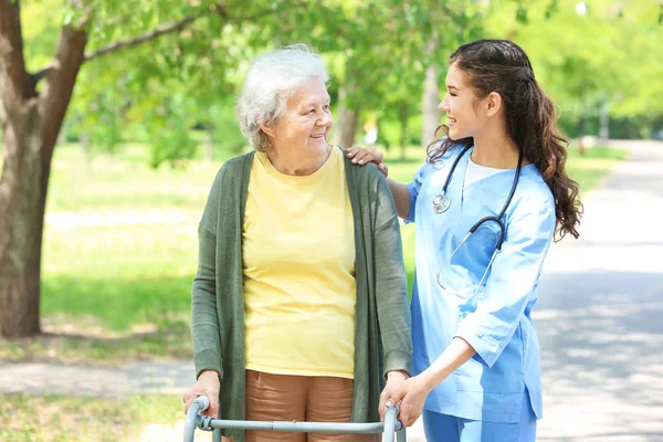 Caregiver walking with senior woman in park — Stock Photo, Image