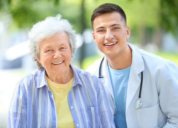 Doctor walking with senior woman in park — Stock Photo, Image
