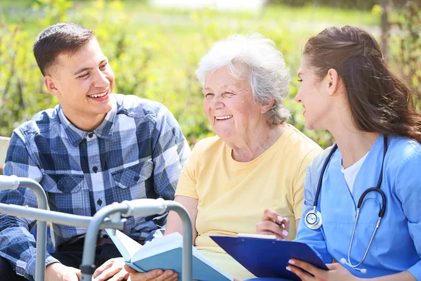 Caregiver and grandson with senior woman in park — Stock Photo, Image