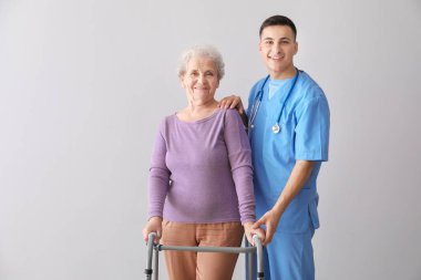 Gri arka plan üzerinde kıdemli kadın ile genç bakıcı