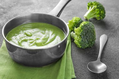 Gri arka planda lezzetli brokoli krema çorbası ile tencere