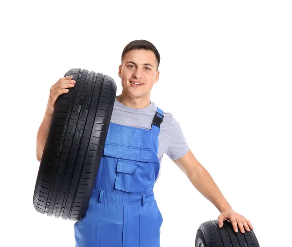 Jeune mécanicien masculin en uniforme avec des pneus de voiture sur fond blanc — Photo