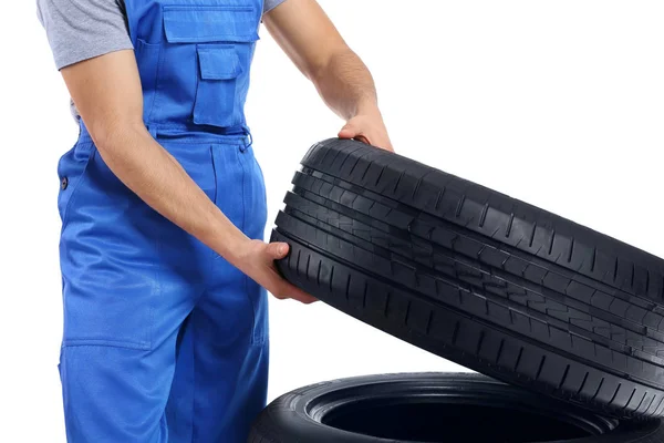 Jovem mecânico masculino em uniforme com pneus de carro no fundo branco — Fotografia de Stock