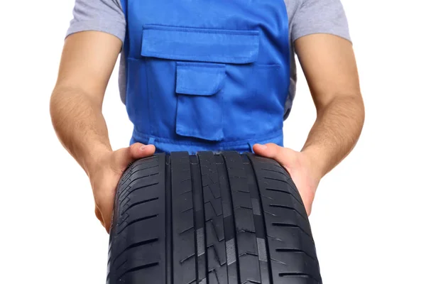 Jeune mécanicien masculin en uniforme avec pneu de voiture sur fond blanc, gros plan — Photo