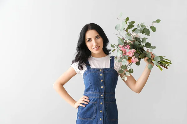 Portrait of beautiful woman with bouquet on light background — Stock Photo, Image