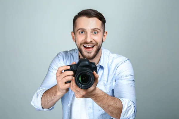 Handsome male photographer on light background — Stock Photo, Image