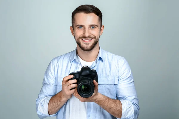 Handsome male photographer on light background — Stock Photo, Image