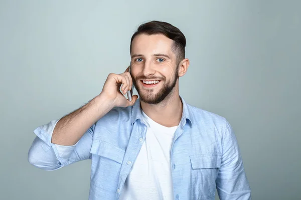 Handsome man talking by phone on light background — Stock Photo, Image