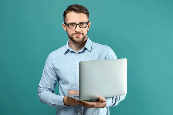 Handsome man with laptop on color background — Stock Photo, Image