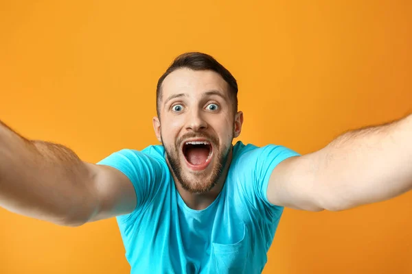 Grimacing man het nemen van selfie op kleur achtergrond — Stockfoto