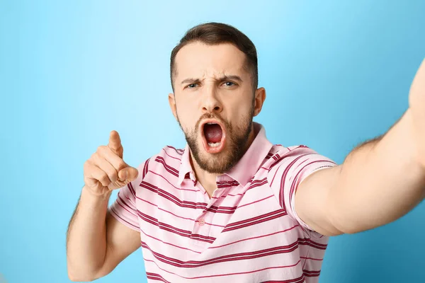 Grimacing man het nemen van selfie op kleur achtergrond — Stockfoto