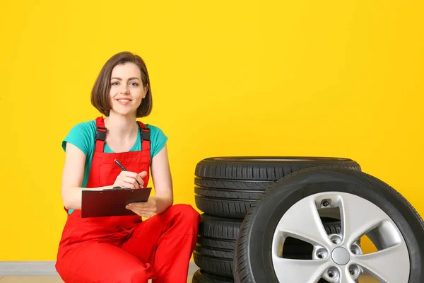 Mladá ženská mechanika v uniformě a s autonehoda blízko barevné zdi — Stock fotografie