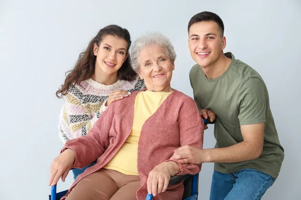 Jonge vrouw en man met grootmoeder op grijze achtergrond — Stockfoto