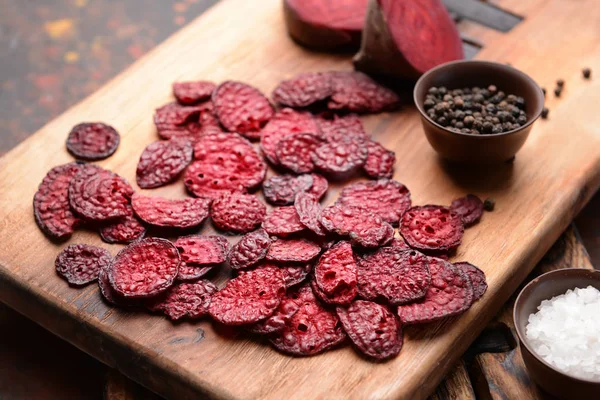 Tasty beet chips with spices on wooden board — Stock Photo, Image