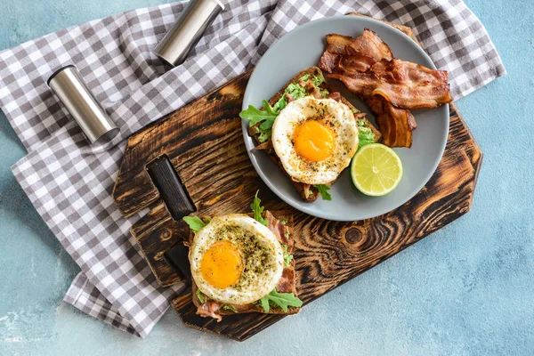 Välsmakande rostat bröd med bacon och stekt ägg på färg bakgrund — Stockfoto