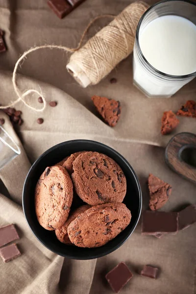 Tál finom csokoládé cookie-k és egy pohár tejet az asztalra — Stock Fotó