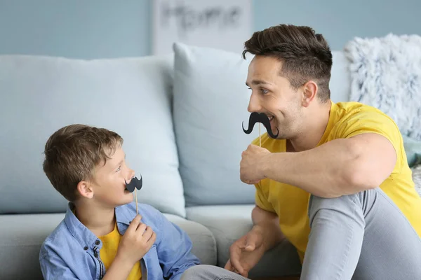 Porträt lustiger Vater und Sohn mit falschem Schnurrbart zu Hause — Stockfoto