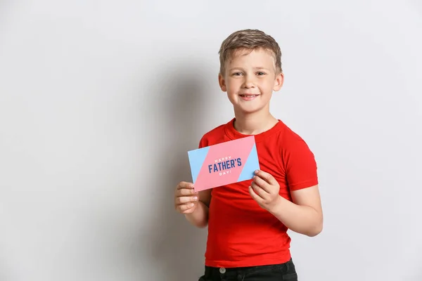 Little boy holding greeting card for Father's Day on light background — Stock Photo, Image