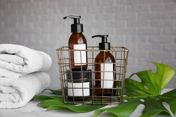 Shampoo, towels and tropical leaf on table — Stock Photo, Image