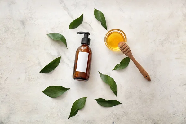 Bottle of shampoo, leaves and honey on light background — Stock Photo, Image