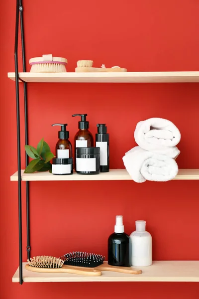 Shampoo, brushes and towels on shelves near color wall — Stock Photo, Image