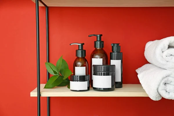 Shampoo and towels on shelf near color wall — Stock Photo, Image