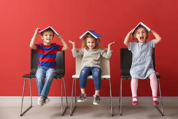 Lindos niños pequeños con libros cerca de la pared de color — Foto de Stock