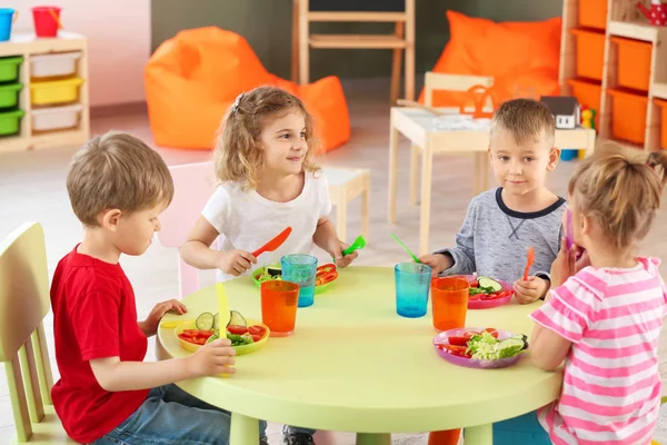 Lindos niños pequeños comiendo sabroso almuerzo en el jardín de infantes — Foto de Stock