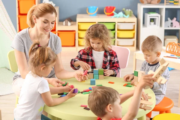 Nursery teacher with cute little children in kindergarten — Stock Photo, Image