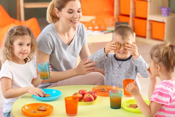 Professeur de maternelle avec de petits enfants mignons pendant le déjeuner à la maternelle — Photo