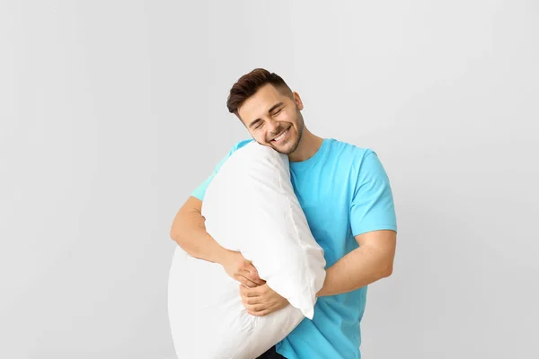 Красивый мужчина обнимает подушку на белом фоне — стоковое фото