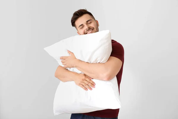 Bonito homem abraçando travesseiro contra fundo branco — Fotografia de Stock