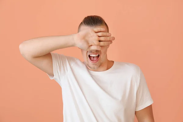 Young man covering his eyes on color background — Stock Photo, Image