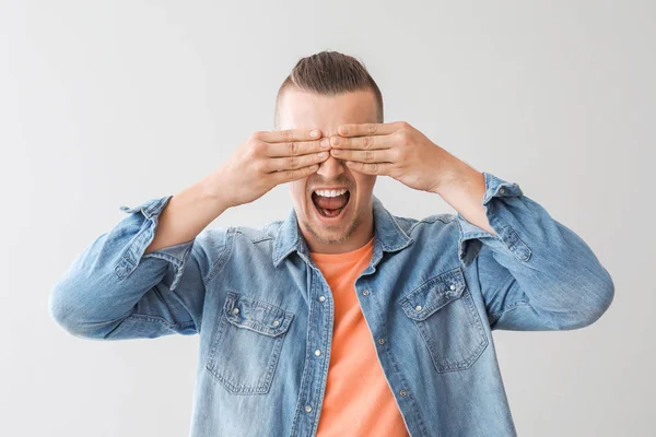 Young man covering his eyes on grey background — Stock Photo, Image