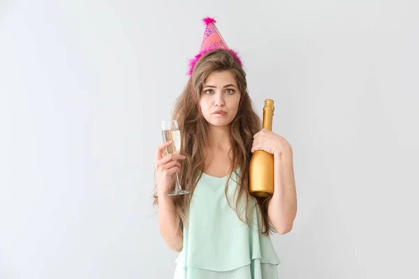 Drunk woman with party hat and champagne on light background — Stock Photo, Image
