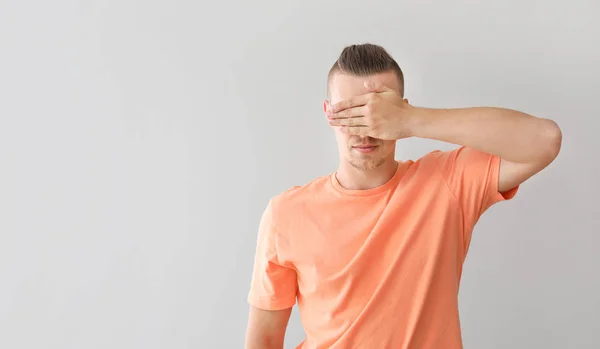 Young man covering his eyes on grey background — Stock Photo, Image