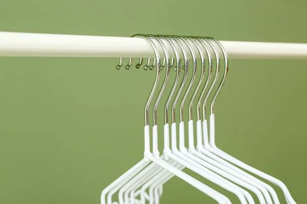 Rack with clothes hangers on color background, closeup — Stock Photo, Image