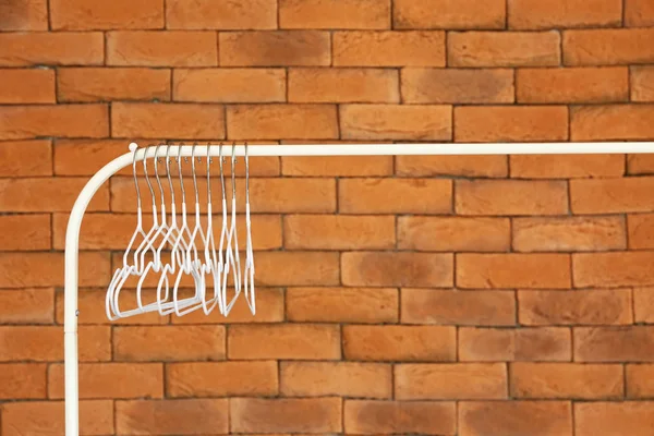 Rack with clothes hangers against brick wall — Stock Photo, Image