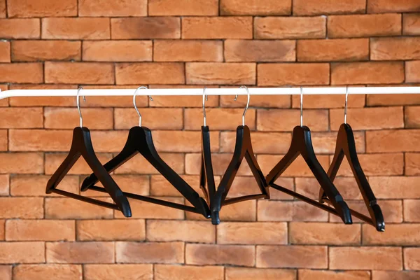 Rack with clothes hangers against brick wall — Stock Photo, Image