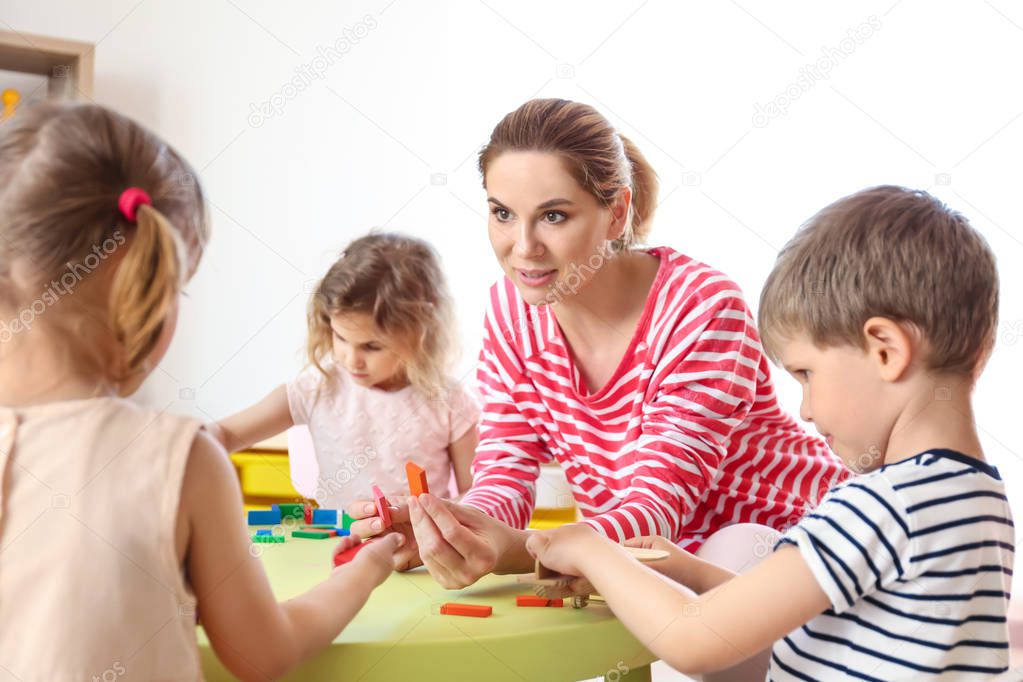 Nursery teacher with cute little children in kindergarten