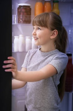 Sevimli küçük kız geceleri buzdolabında yiyecek seçerek