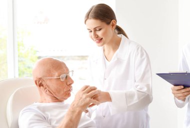 Doktor klinikte yaşlı adama su veriyor