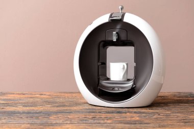 Renkli arka plana karşı masada fincan ile modern kahve makinesi
